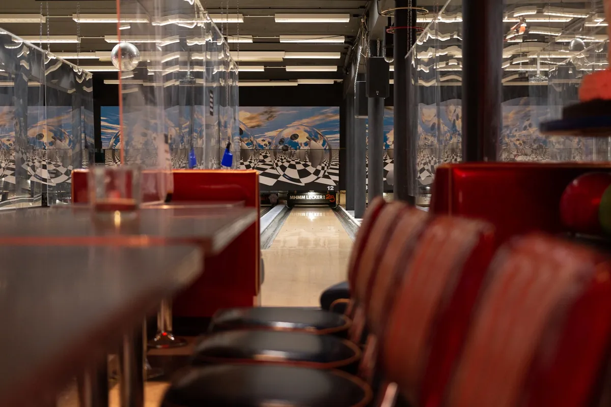 Sitzreihen und Tische direkt an den Bowlingbahnen